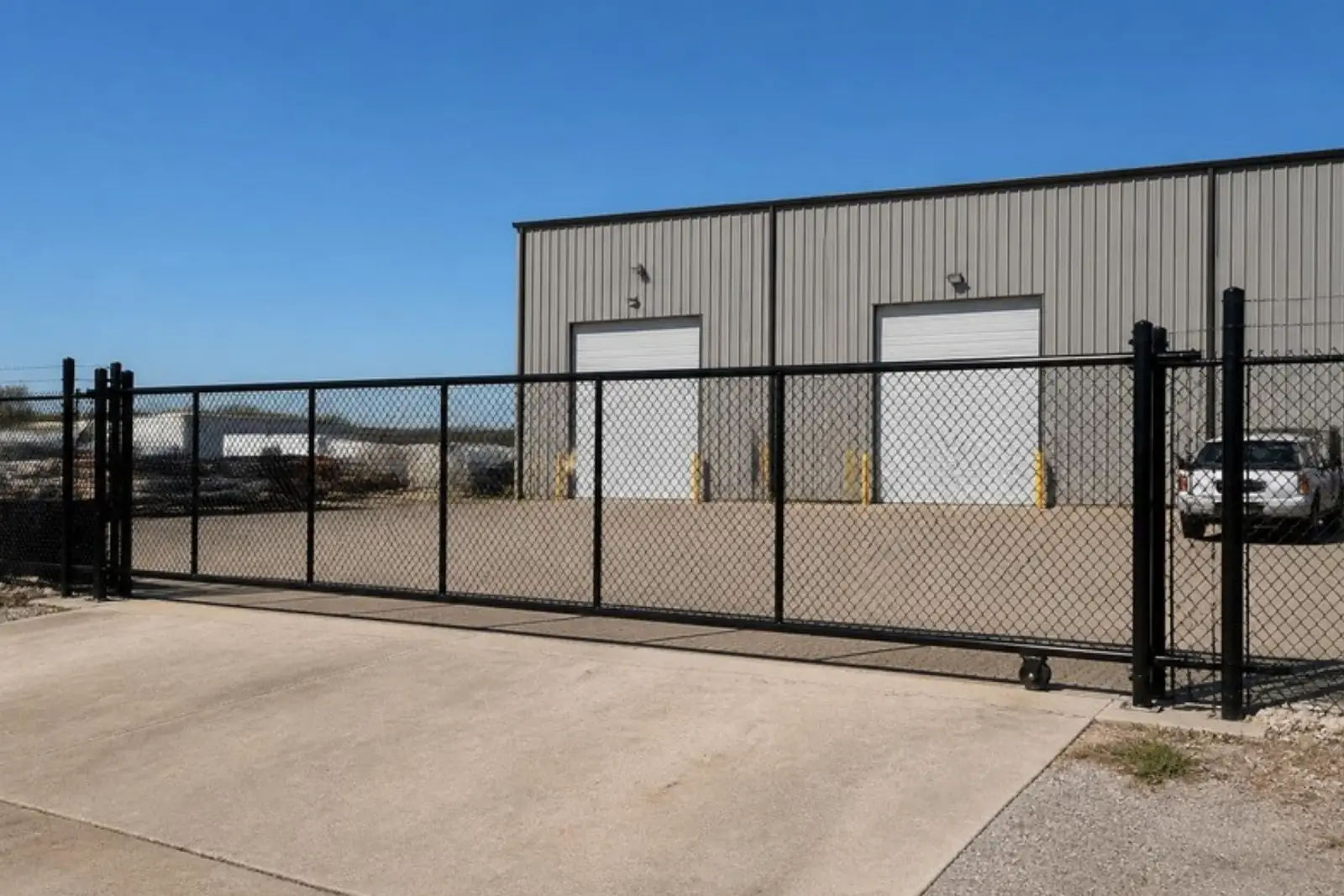 Tall commercial fence with a rolling gate at a warehouse lot
